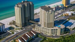 Un hotel di grandi dimensioni con numerosi piani, un parcheggio e vista sulla spiaggia.