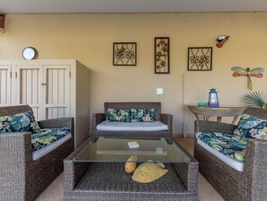 A living room with wicker furniture, a glass coffee table, and decorative wall art.