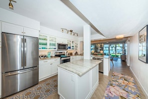 A modern kitchen with stainless steel appliances, white cabinetry, and a central island. - Waterfront 2BR condo with pool, hot tub, balcony, and water views. (St Petersburg)