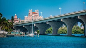 Uma ponte com várias arcos que atravessa um corpo de água, com edifícios ao fundo.