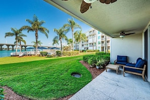 A hotel patio with a view of a bridge, palm trees, and a pool.