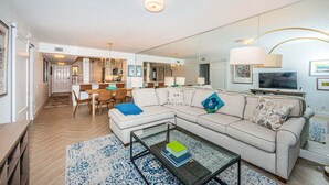 Uma sala de estar moderna com sofá, mesa de centro e área de jantar com cadeiras e mesa.