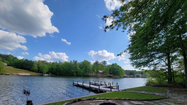 Une terrasse au bord du lac, avec des fauteuils Adirondack, un foyer et une jetée qui s’avance dans l’eau.