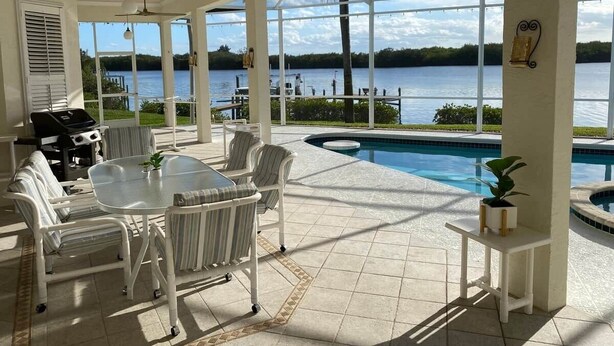 An outdoor patio with a pool, a grill, and chairs. - 4-Bedroom Villa with Pool & Jacuzzi, Mangrove View (Port St. Lucie)