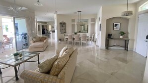 A spacious living area with a sofa, a dining table, and a kitchen in the background. - 4-Bedroom Villa with Pool & Jacuzzi, Mangrove View (Port St. Lucie)