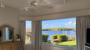 A bedroom with a large window, a bed, a dresser, a ceiling fan, and a TV. - 4-Bedroom Villa with Pool & Jacuzzi, Mangrove View (Port St. Lucie)