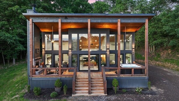 Een moderne blokhut met een houten terras, grote ramen en een open haard.