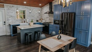 Een moderne keuken met blauwe kastjes, een centraal eiland, roestvrijstalen apparatuur en een houten plafond.