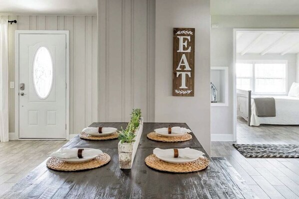 Enjoy meals in this traditional dining area with a table for four, featuring woven placemats and a decorative sign.