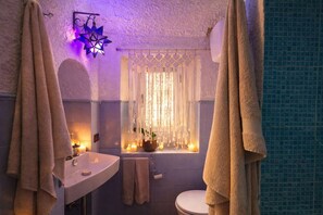 A bathroom with a bathtub, a sink, a toilet, and a window with curtains.