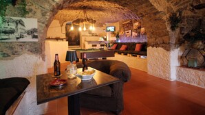Eine gemütliche Bar mit rustikalem Kaminbogen, einem Billardtisch und bequemen Sitzgelegenheiten.