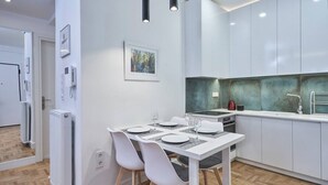 A modern kitchen with white cabinets, a dining table set for four, and a green backsplash. - Hilton-Ilisia Park 2Bd Elite Living (Athina)