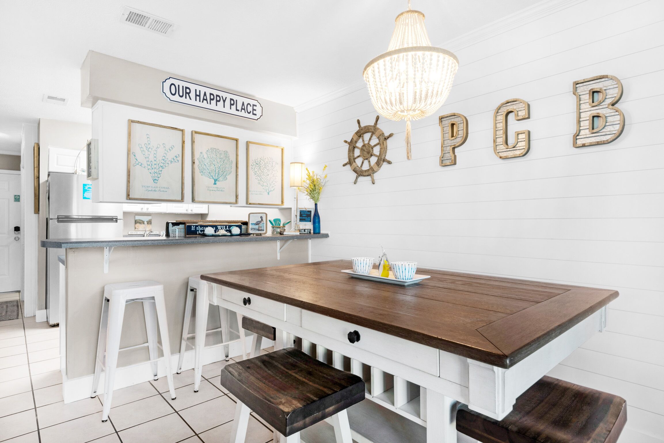 A kitchen with a wooden island, white cabinetry, and a sign that reads 'OUR HAPPY PLACE'.