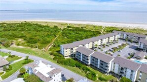 An aerial view of a coastal residential area with apartment buildings, a beach, and a golf course. - Your Tybee Island Escape – Oceanfront Condo 20C (Tybee Island)