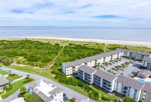 Una vista aerea di una zona residenziale costiera con palazzi, una spiaggia e un campo da golf.
