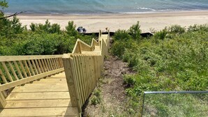 Eine Holztreppe führt zu einem Strand mit freiem Blick auf den Ozean.