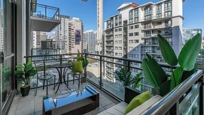 Ein Balkon mit Glastisch, Stühlen und Blumentöpfen.
