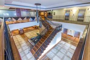 A multi-level interior with a central staircase, wooden flooring, and metal railings.