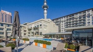 Ein Hotel mit Außenbestuhlung, einem Pool und Blick auf den CN Tower.