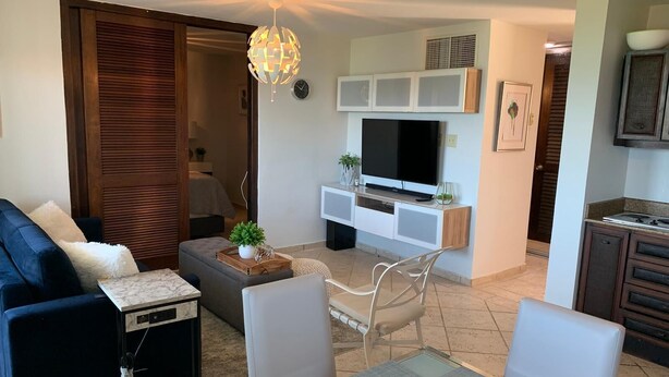 Un salon moderne comprenant un canapé, une table à manger, un téléviseur et un coin cuisine.