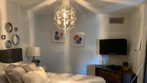 Une chambre à coucher avec un grand lit, une télévision, une commode et un lampadaire décoratif en forme de globe.