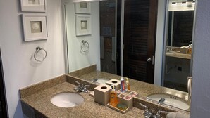 Une salle de bain avec deux lavabos, un grand miroir et un meuble-lavabo avec des articles de toilette.