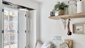 A room with a large window, a wooden shelf with jars and a picture frame, and a small speaker on a windowsill. - Sea air and starry nights - there's space for two and your four legged friend. (Cromer)