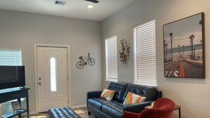 A living room with a black leather sofa, a red armchair, a television, and a painting of a beach scene. - Great location and Balcony Views! Fun in the Sun (Galveston)