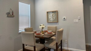 A dining area with a table set for four, surrounded by upholstered chairs. - Great location and Balcony Views! Fun in the Sun (Galveston)