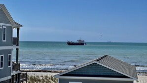 Vista costera con una casa y un barco a lo lejos.