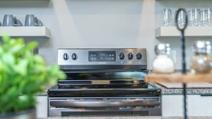 Een moderne keuken met een roestvrijstalen afzuigkap, een ingebouwde oven en een granieten aanrecht.