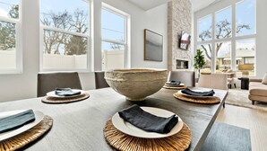 A modern dining area with a large stone bowl centerpiece, a fireplace, and large windows offering views of the outdoors.