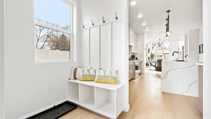A modern interior with a white color scheme, a built-in bench with cushions, a kitchen area, and a dining space.