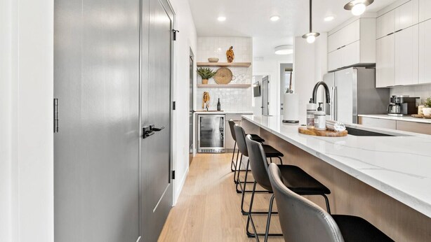 A modern kitchen with a central island, bar stools, and a built-in oven.