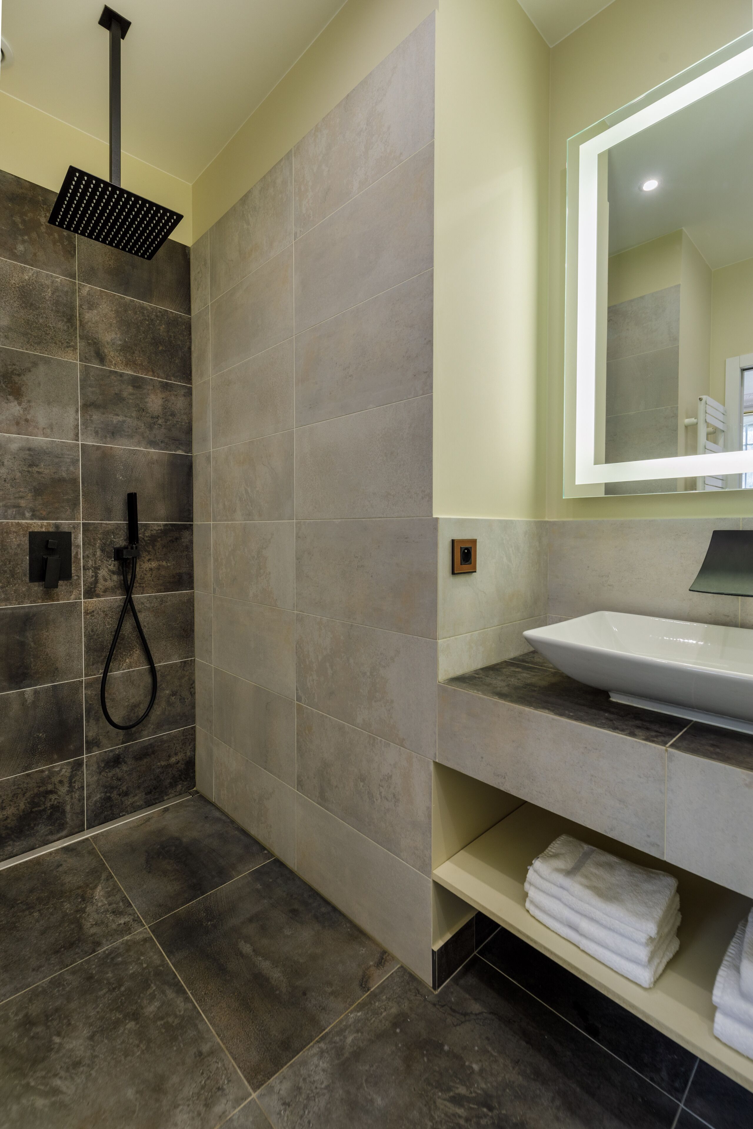 Une salle de bain moderne avec une douche, un lavabo et un miroir.