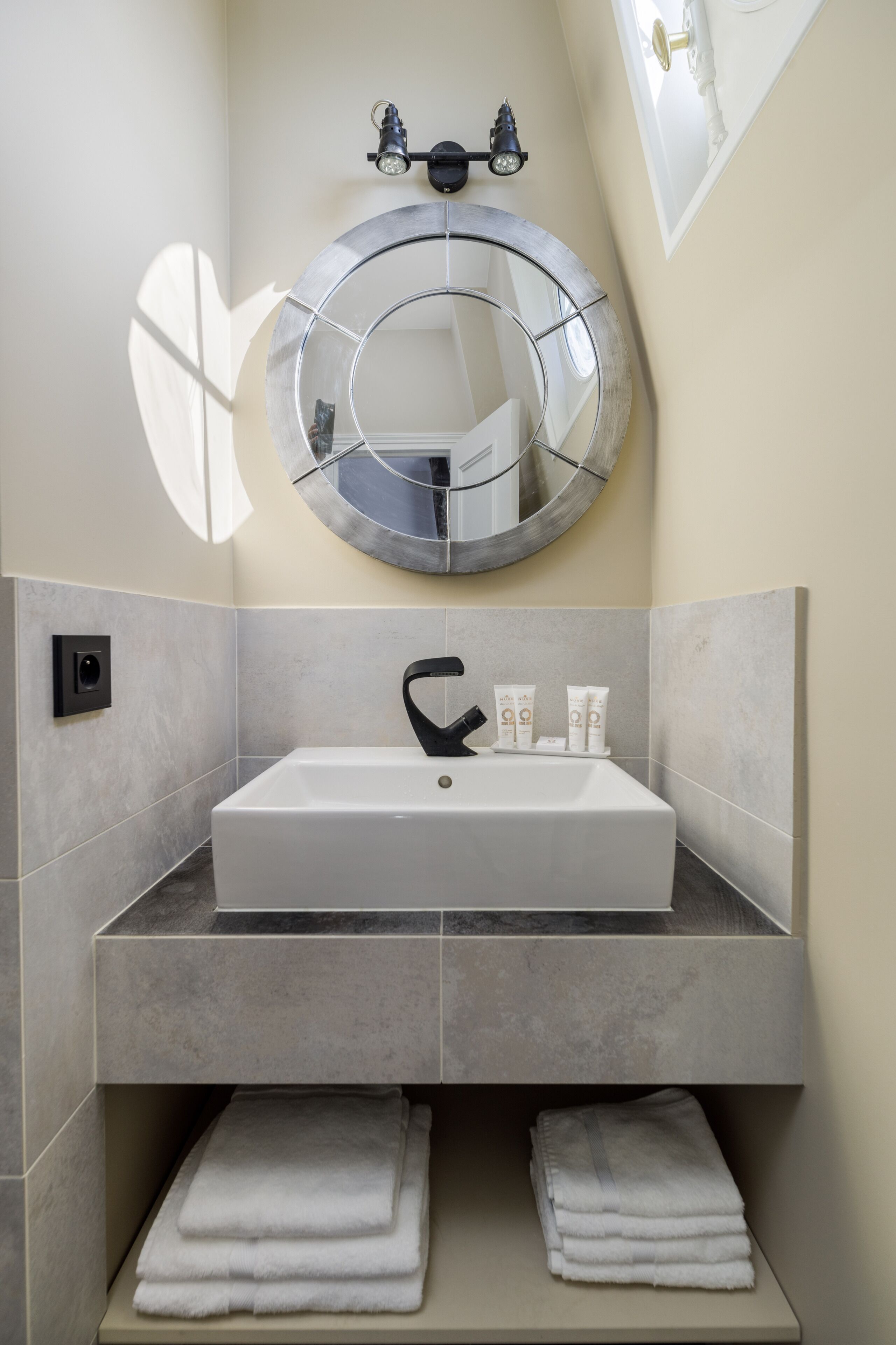 Une salle de bain avec un grand miroir, un lavabo et deux porte-serviettes.
