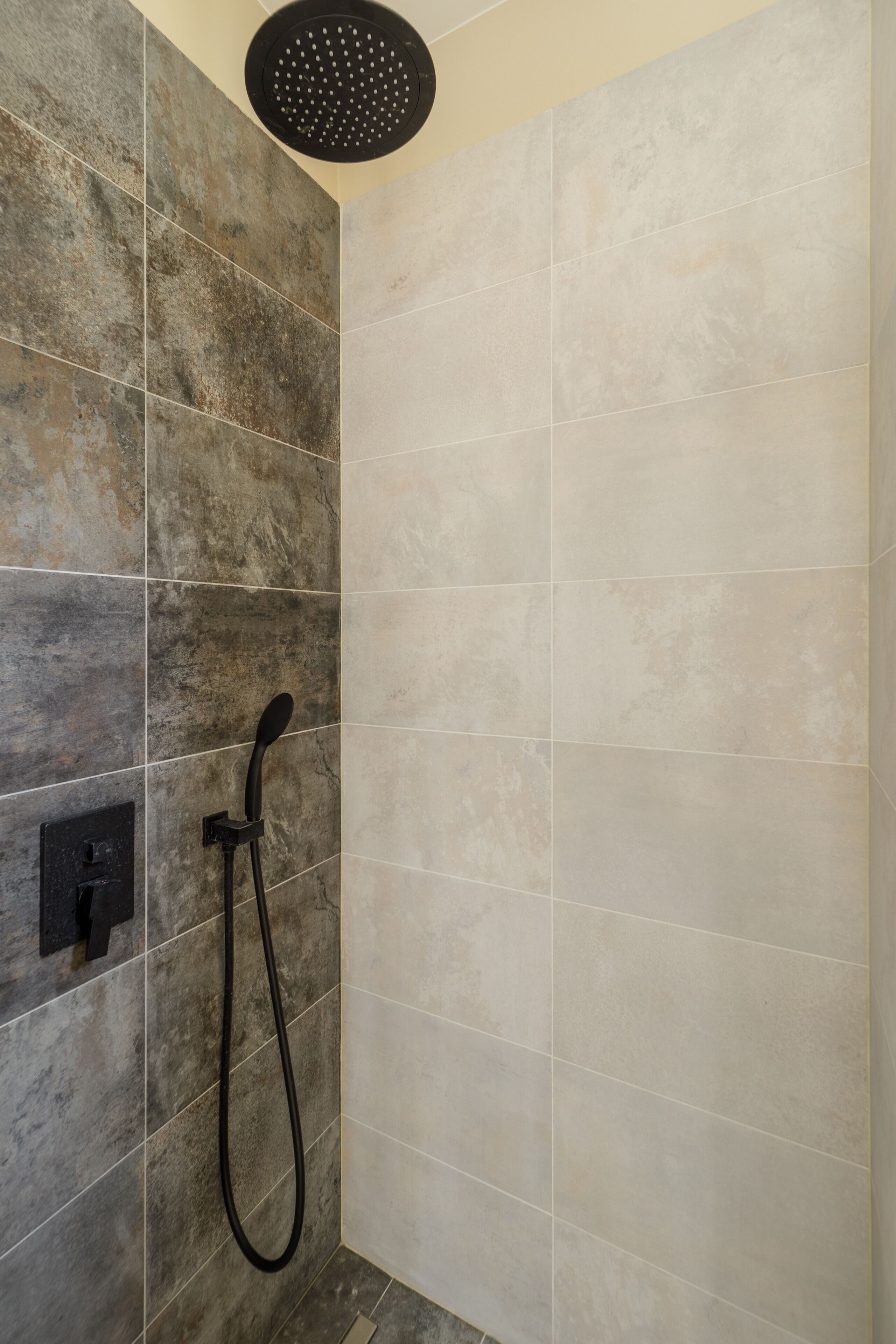 A shower area with a rain showerhead and a handheld showerhead.