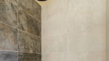 A shower area with a rain showerhead and a handheld showerhead.