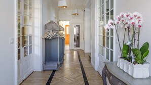 A hallway with a herringbone floor, white doors, and a console table with orchids. - L'Hôtel Particulier (Asnieres-sur-Seine)