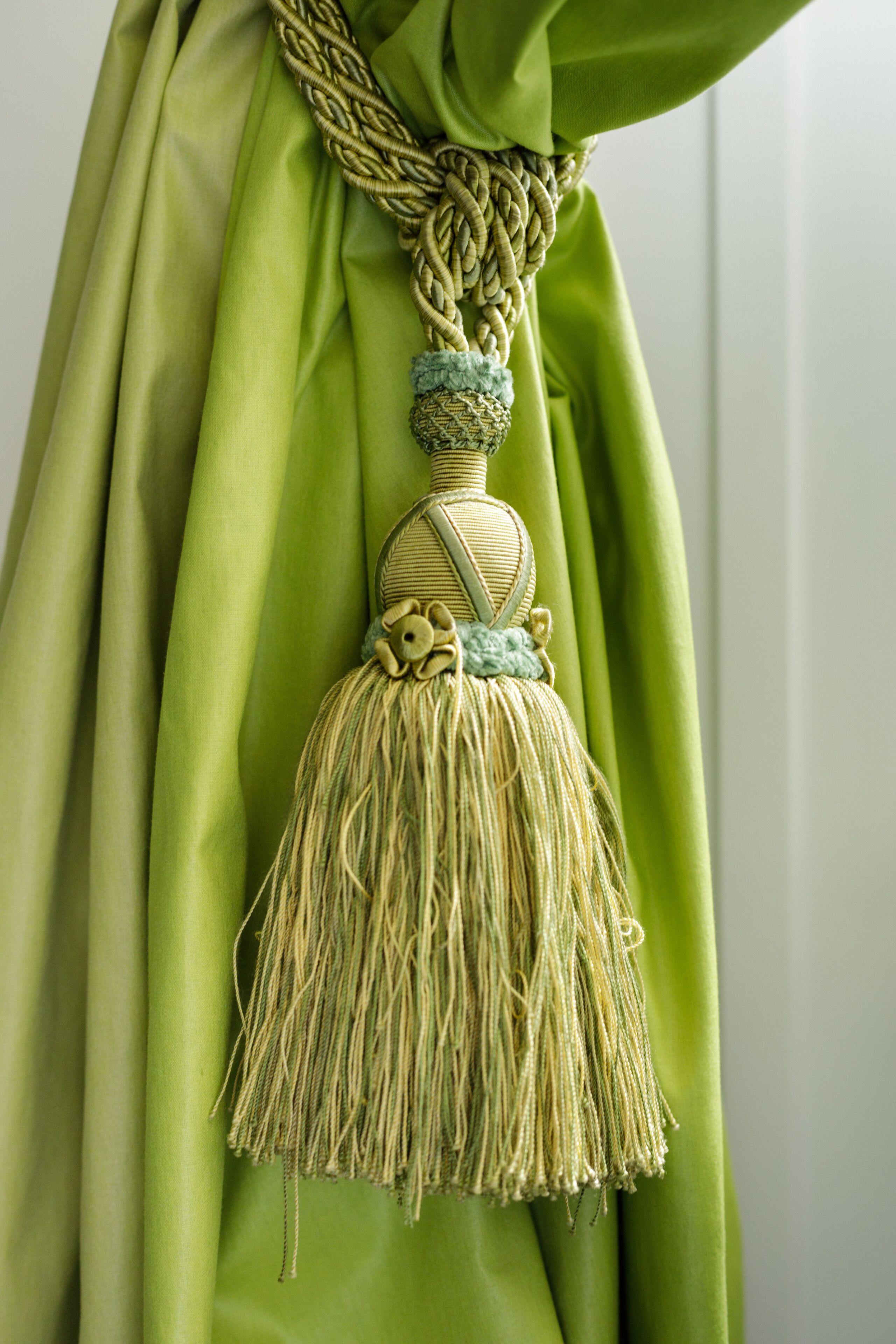 A green curtain with a decorative tassel.