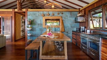A kitchen with a wooden table, hanging light fixtures, and a large stove.