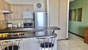 Una cocina moderna con una isla central, electrodomésticos de acero inoxidable y un reloj en la pared.