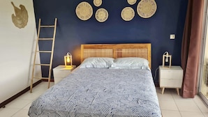 Un dormitorio con cama, dos mesitas de noche, una escalera de madera y decoración en la pared.