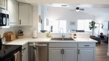 A modern kitchen with white cabinetry, a stainless steel dishwasher, and a black stove.