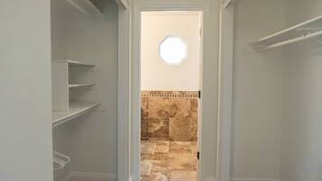 A narrow hallway with white walls, a beige carpet, and a tiled shower area with a small window.
