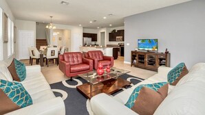 A modern living room with a white sofa, red chairs, and a glass coffee table. - 6 bedroom 5 bathroom with Spa and Games Room Brand New Modern Furnishings (Davenport)