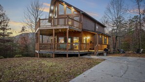 A log cabin with a balcony, a deck, and a front porch.