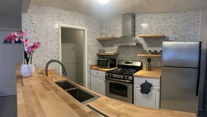 A modern kitchen with a wooden countertop, stainless steel appliances, and a backsplash with a mosaic tile pattern. - ***Southern Home *** (Atlanta)