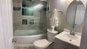A bathroom with a glass-enclosed shower, a white toilet, and a sink with a mirror. - ***Southern Home *** (Atlanta)