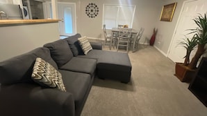 A living room with a sectional sofa, a dining table with chairs, a ceiling fan, and a potted plant. - ***Southern Home *** (Atlanta)